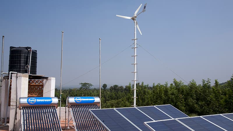 Solar panels on roof with windmill in the distance