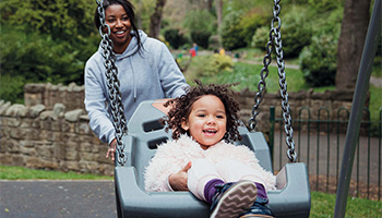Woman pushing child on swing